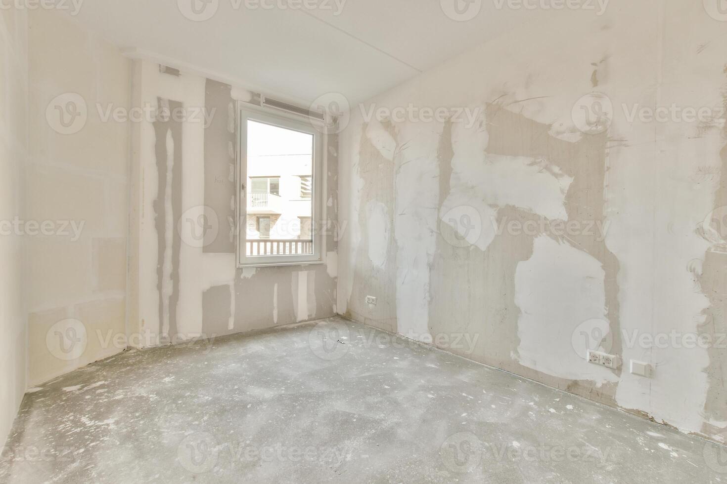 An empty room with a window and a wall covered in drywall photo