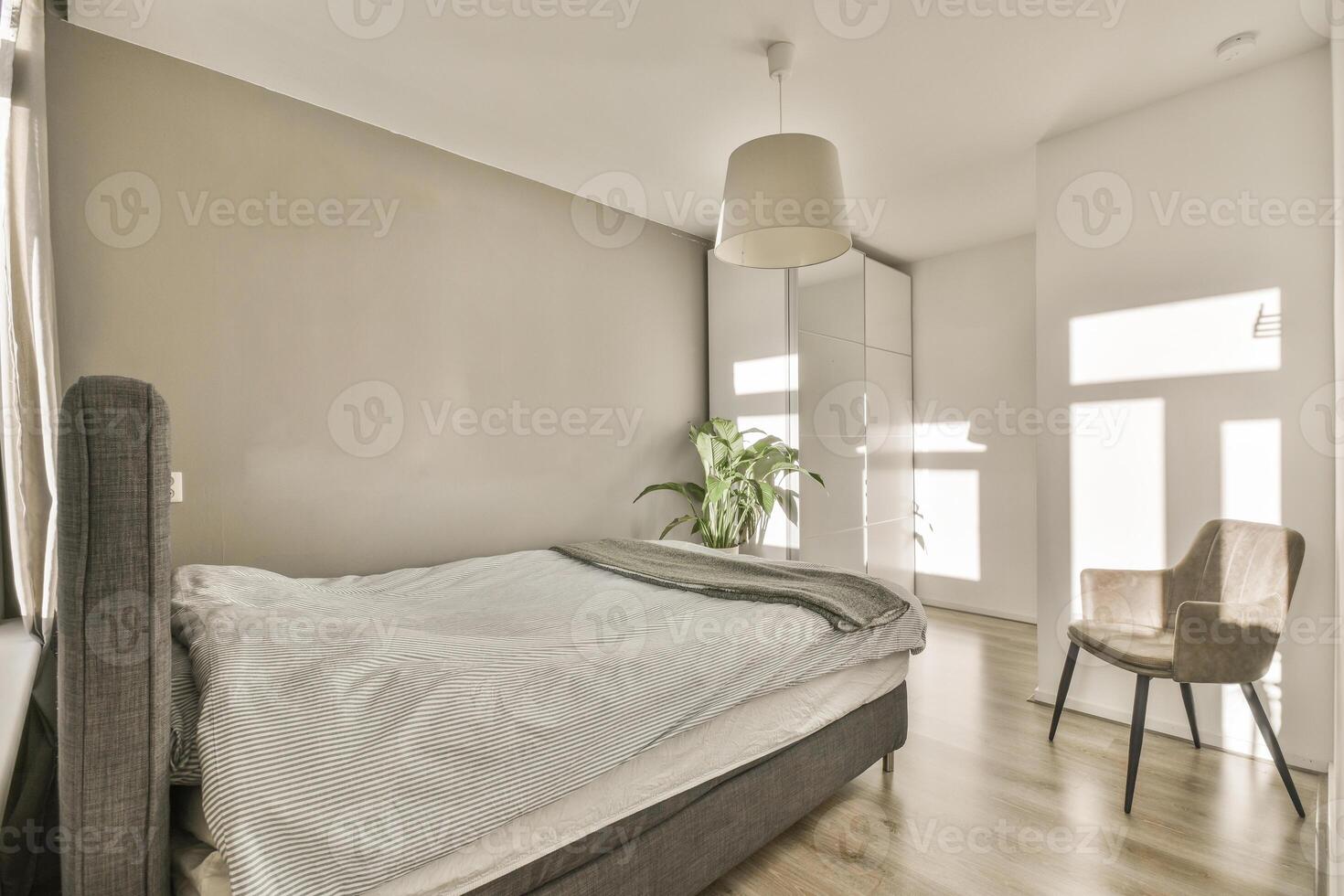 A bedroom with a bed, chair and a plant photo
