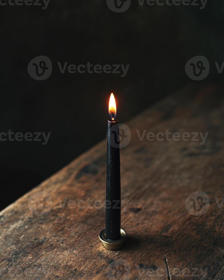 A single black candle burning in a gothic-style holder photo