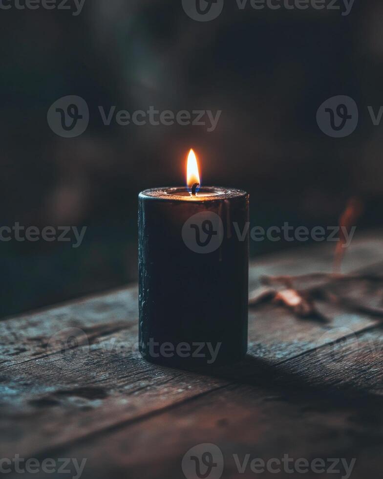 A single black candle burning in a gothic-style holder photo