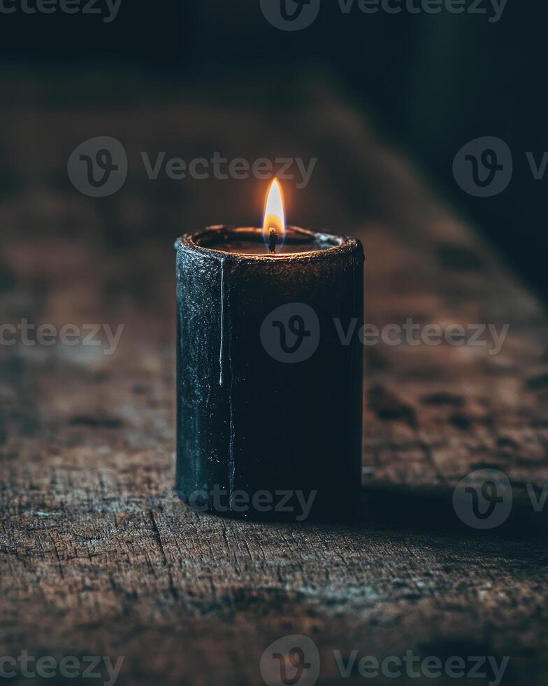 A single black candle burning in a gothic-style holder photo