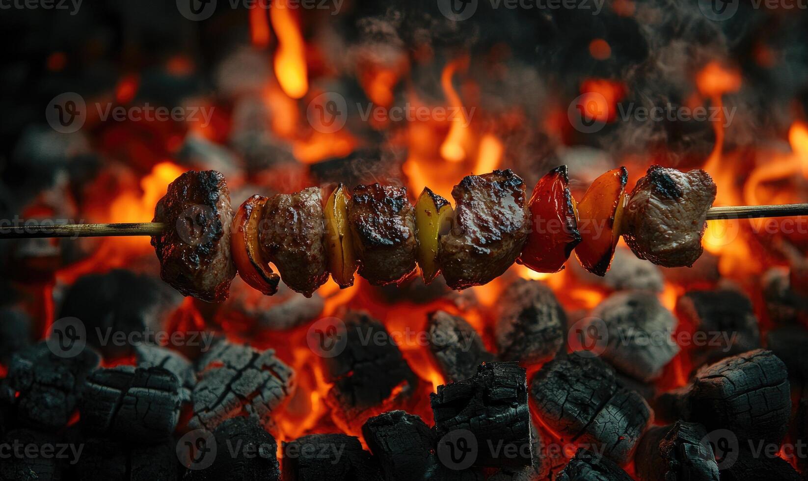 Juicy meat turning on a skewer above glowing hot coals photo