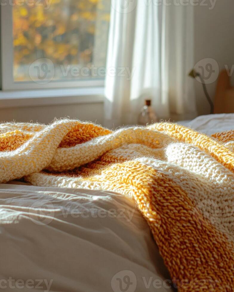 Knitted blanket in fall colors, soft and cozy, resting on the edge of a bed photo