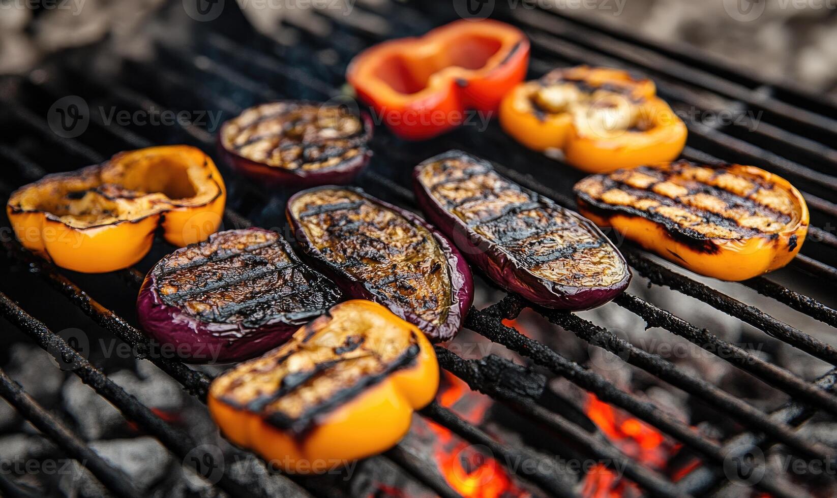 Thick slices of eggplant and peppers grilling over the hot coals photo