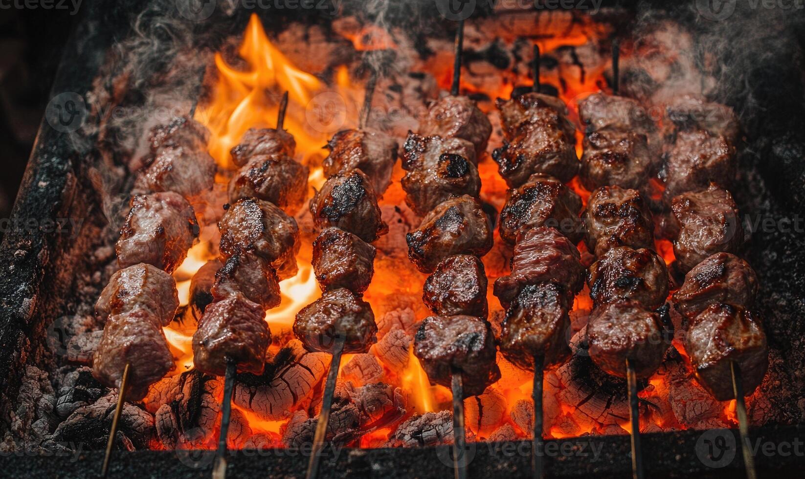 Skewers of lamb shashlik slowly turning over smoldering coals photo