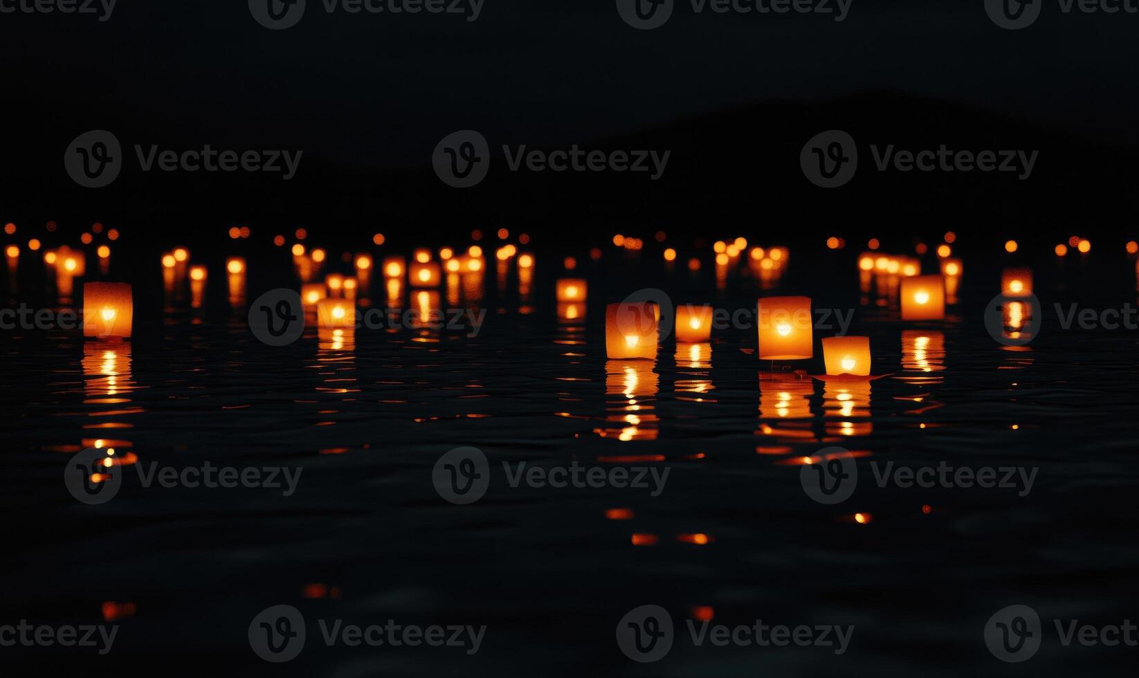 Multiple floating lanterns glowing brightly on a dark river photo