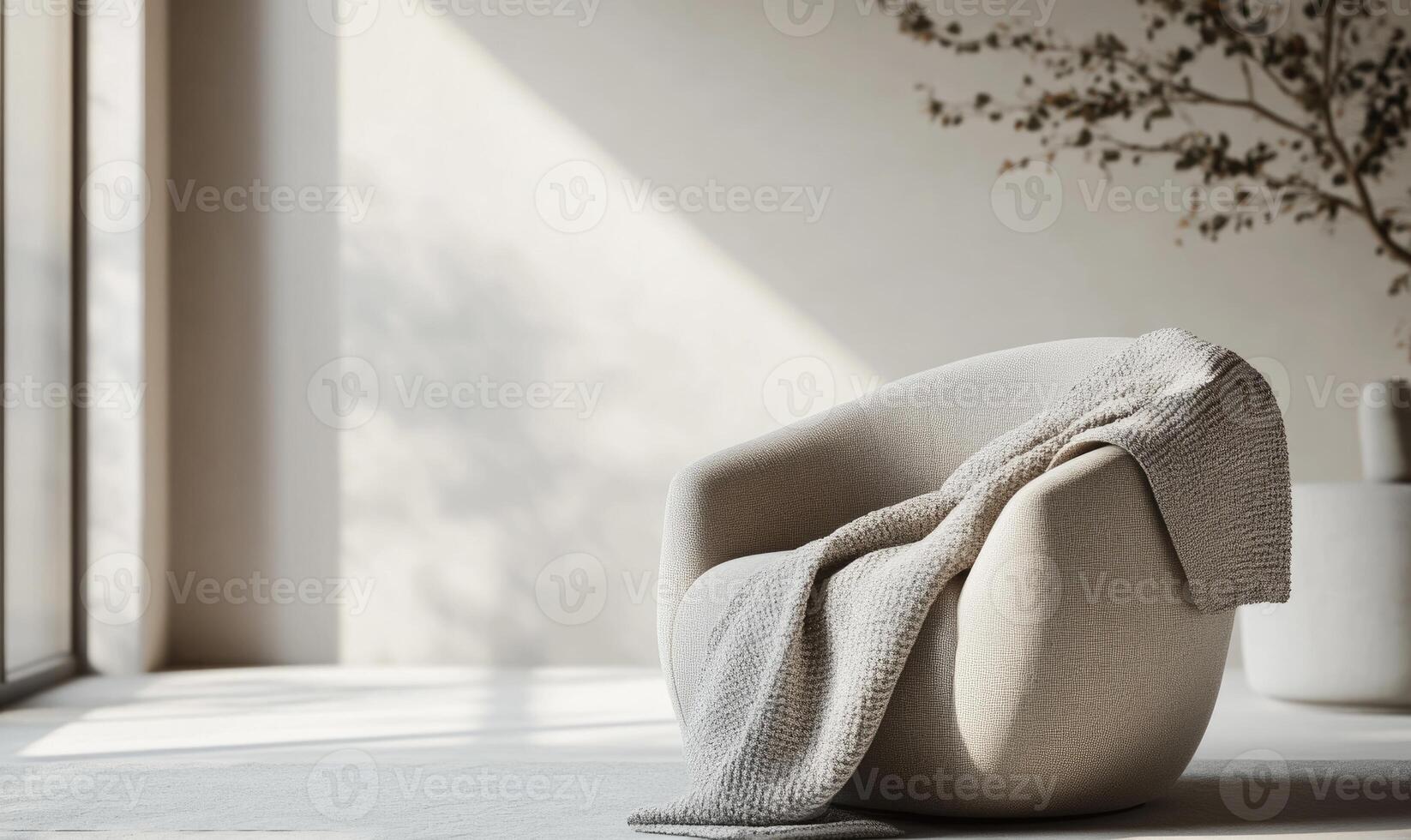 A white chair with a white blanket draped over it sits in a room with a window photo