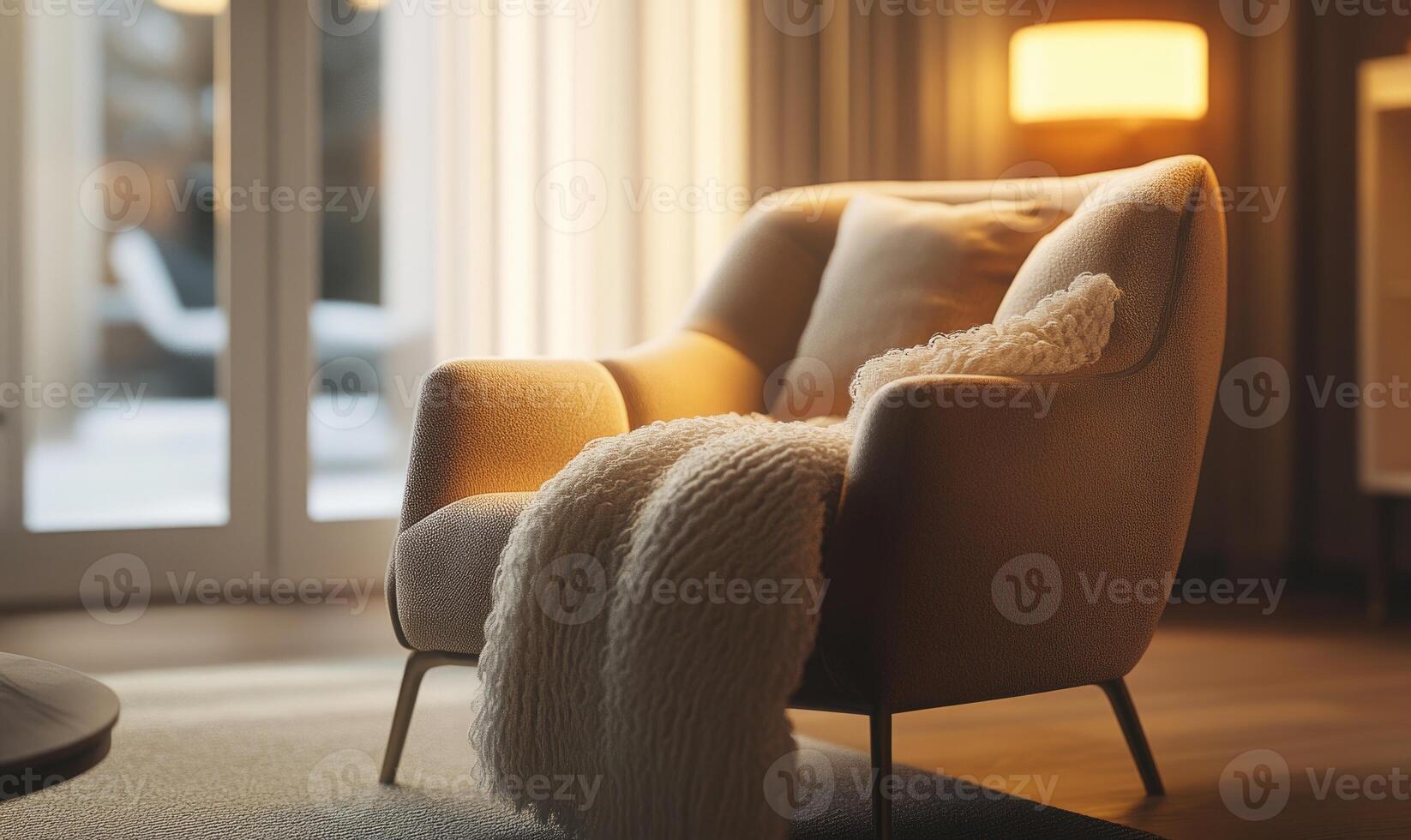 A tan chair with a white blanket draped over it sits in a room with a window photo
