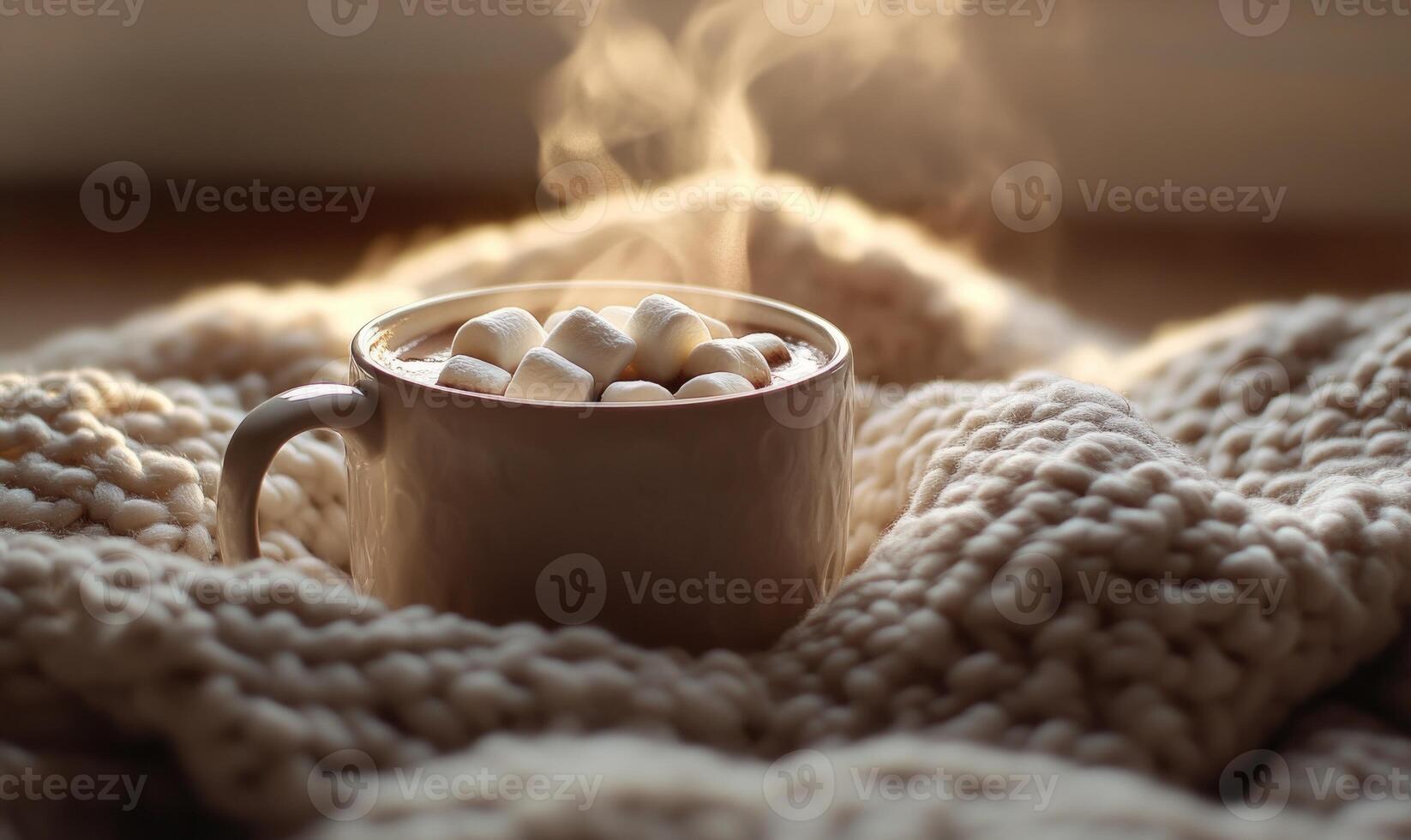 A mug of hot chocolate with marshmallows on top of a blanket photo