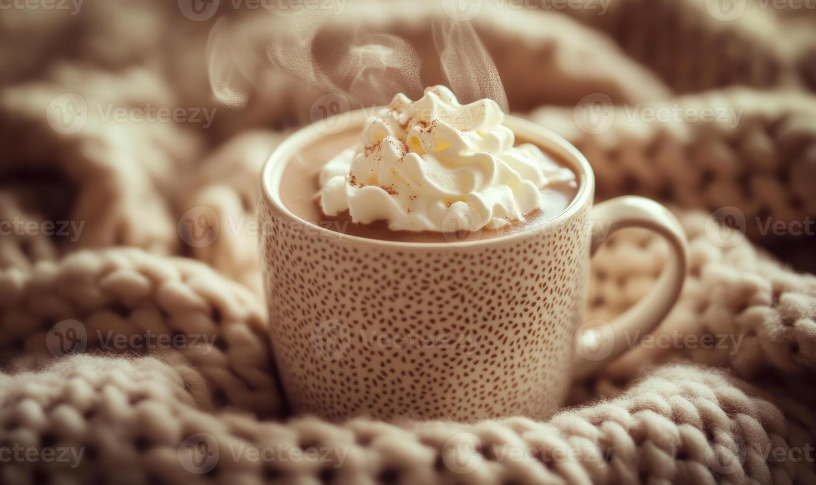 A white coffee cup with whipped cream on top sits on a blanket photo