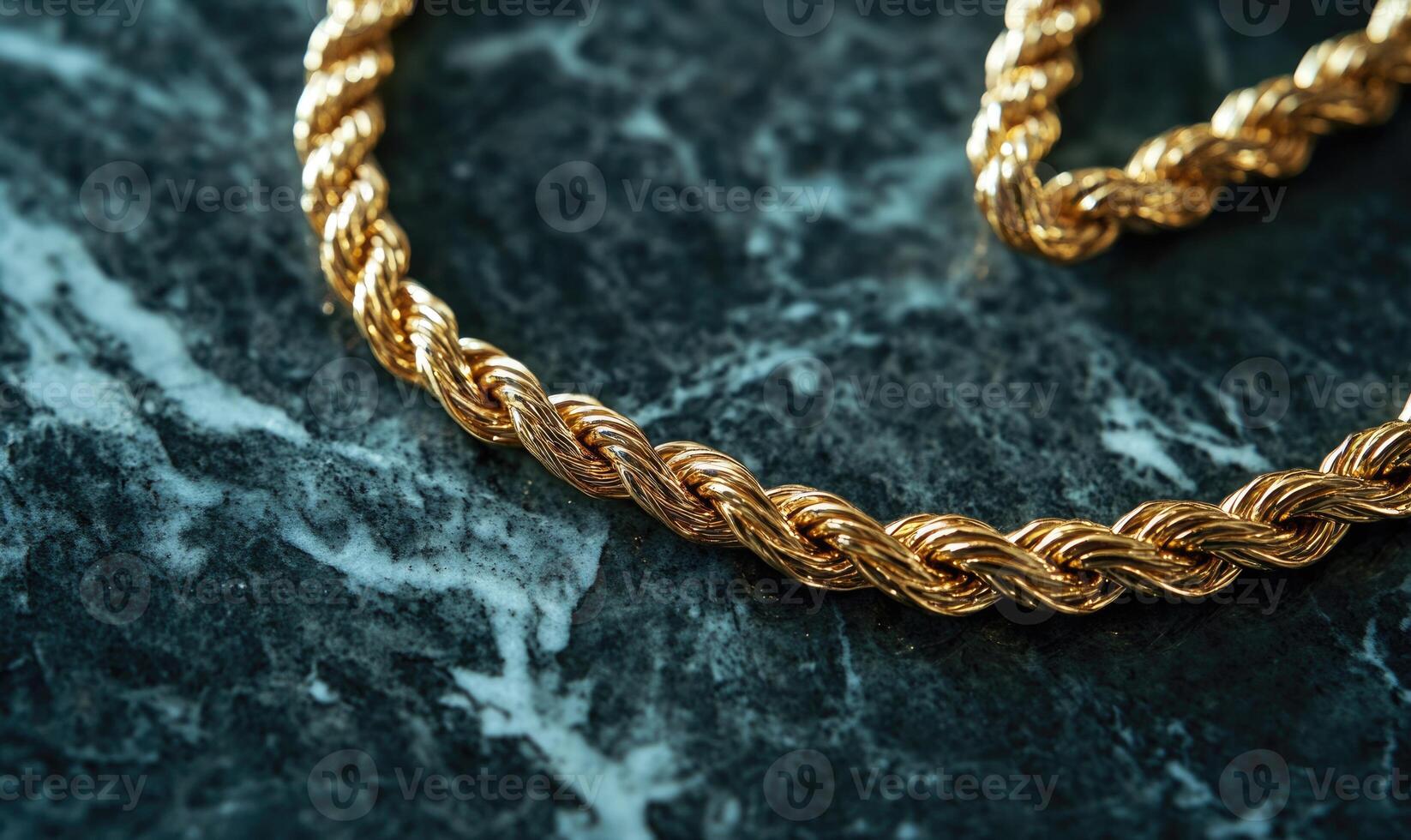 A gold chain with a gold clasp is laying on a marble surface photo