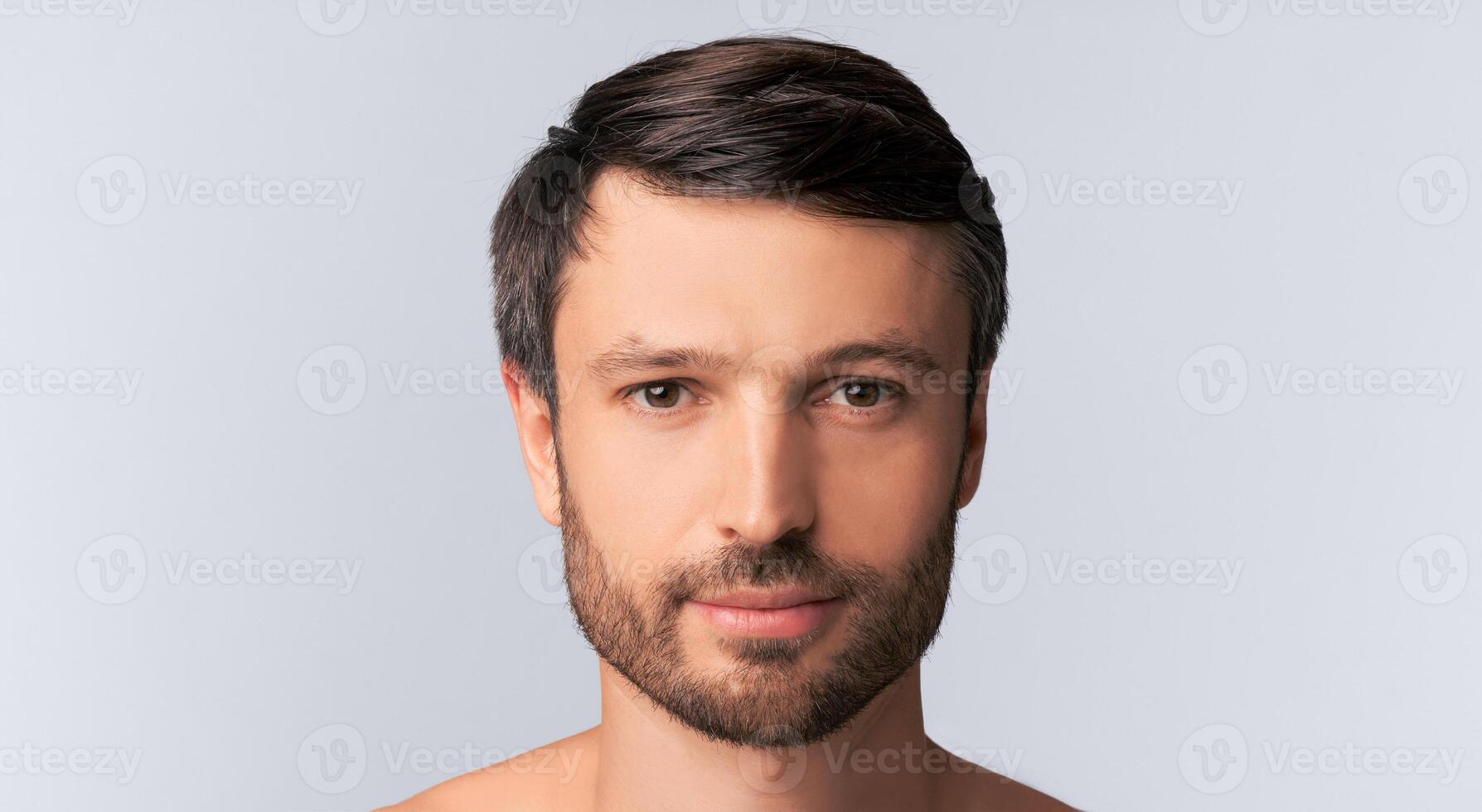 Portrait Of Serious Man Looking At Camera Posing Over White Studio Background. Panorama, Isolated, Empty Space photo
