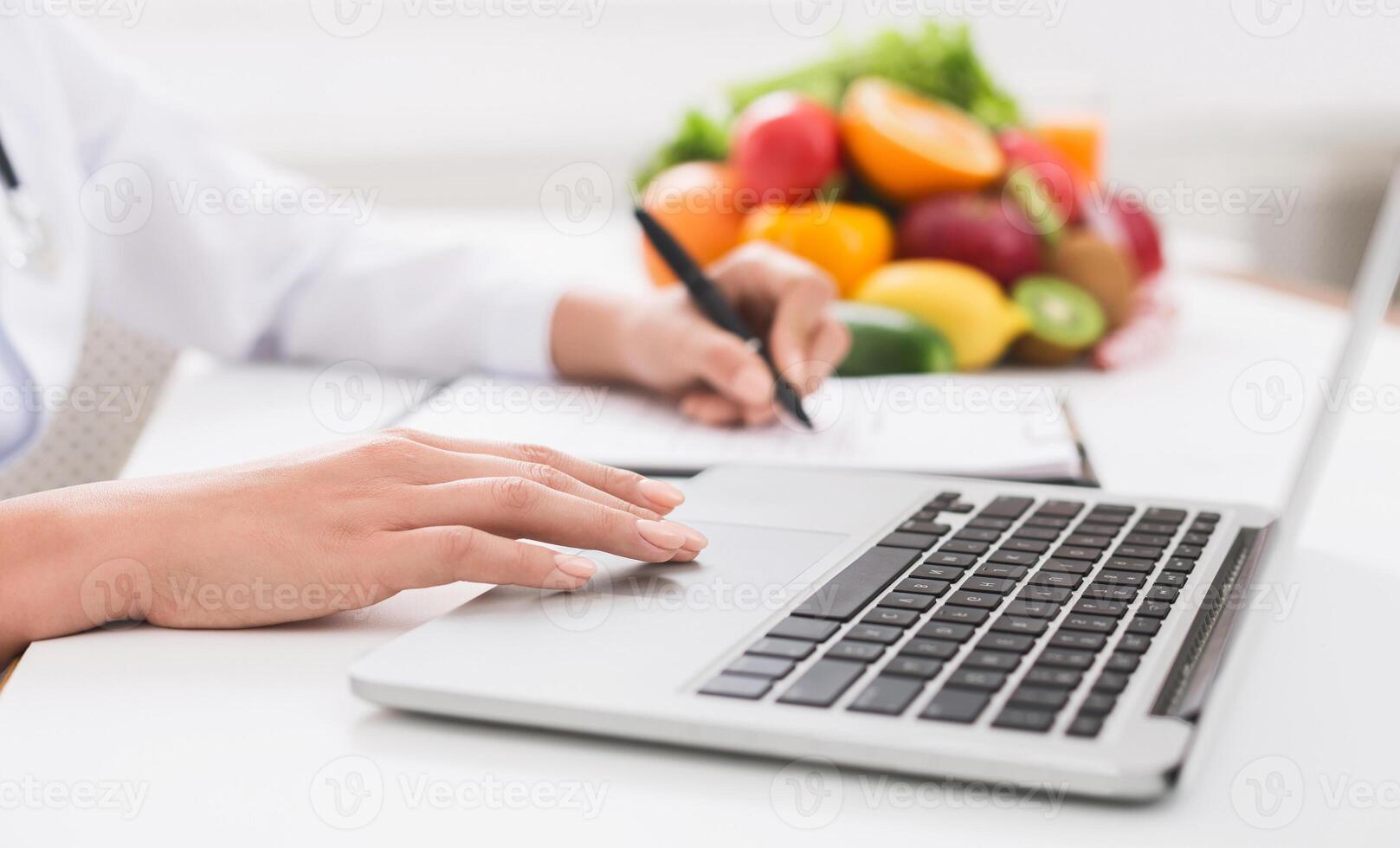 Nutritionist working on laptop and writing diet plan for patient, panorama, copy space photo