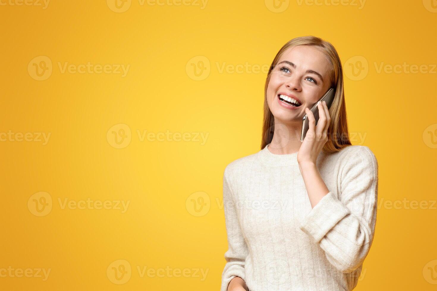 Portrait of beautiful teenage girl talking on phone, orange studio background with copy space photo