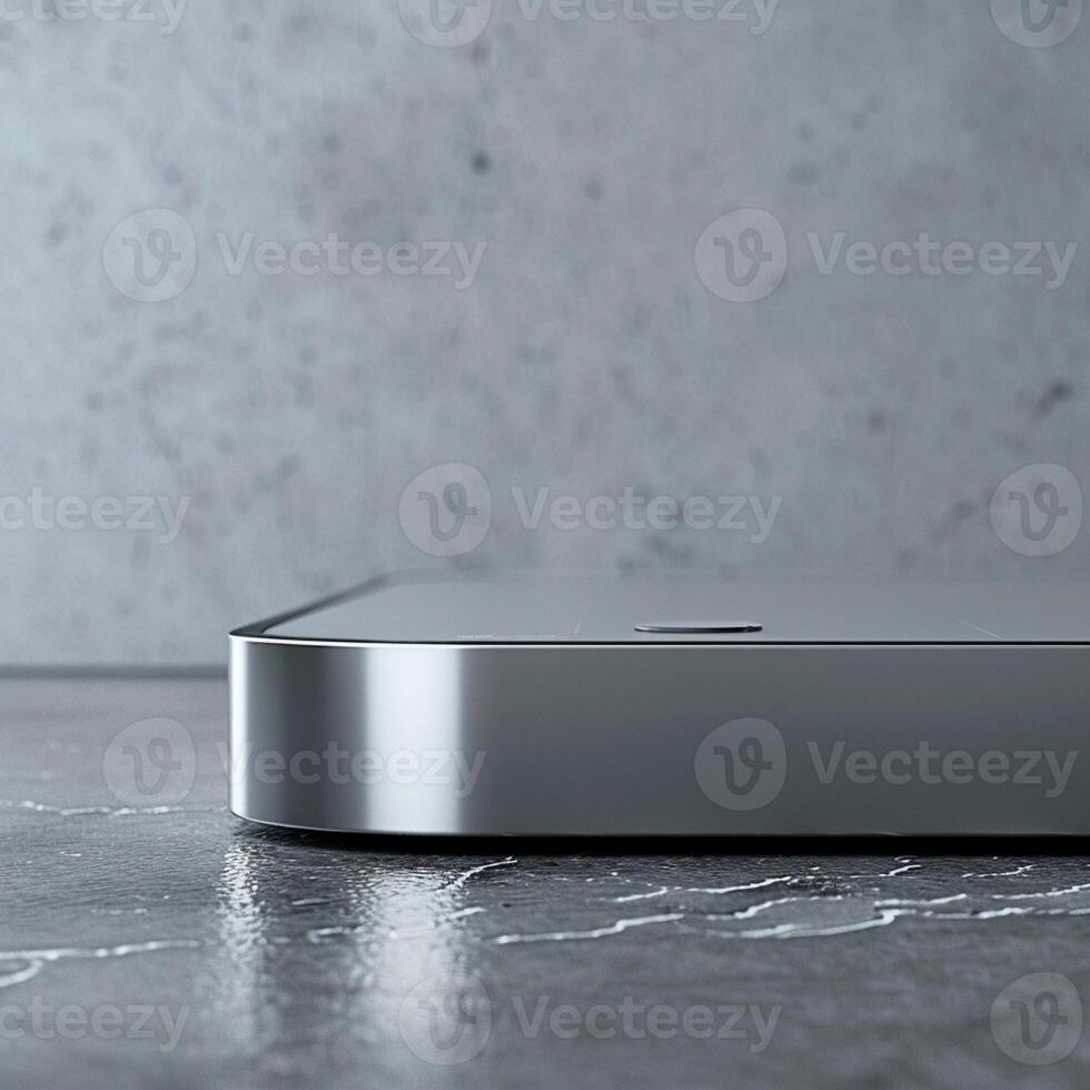 A silver computer on a table with a gray wall photo