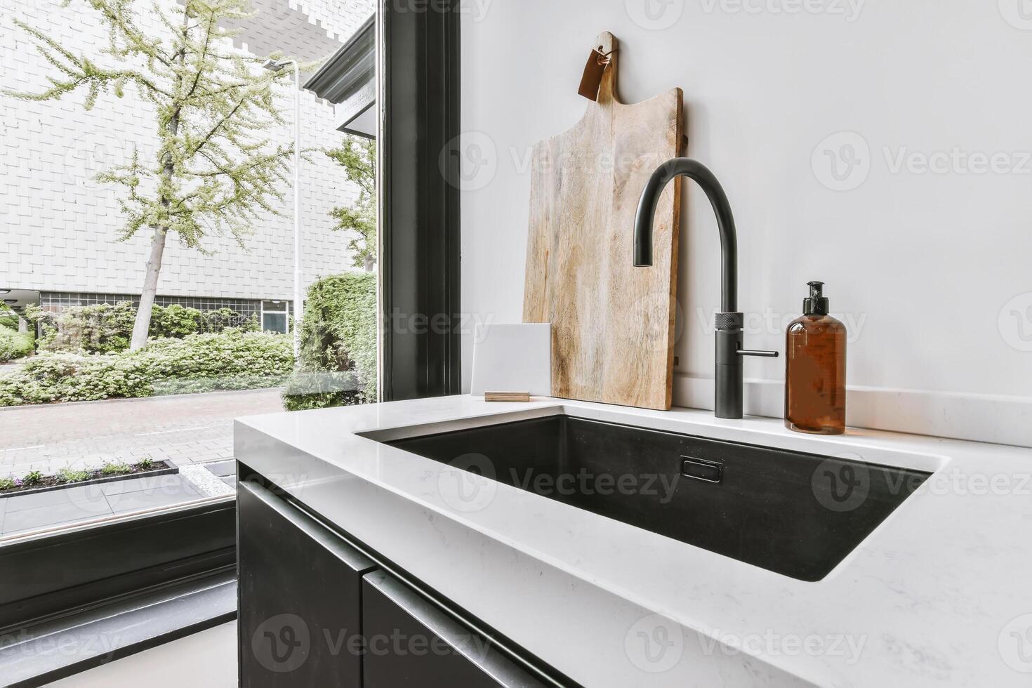 A kitchen sink with a black sink and white counter photo