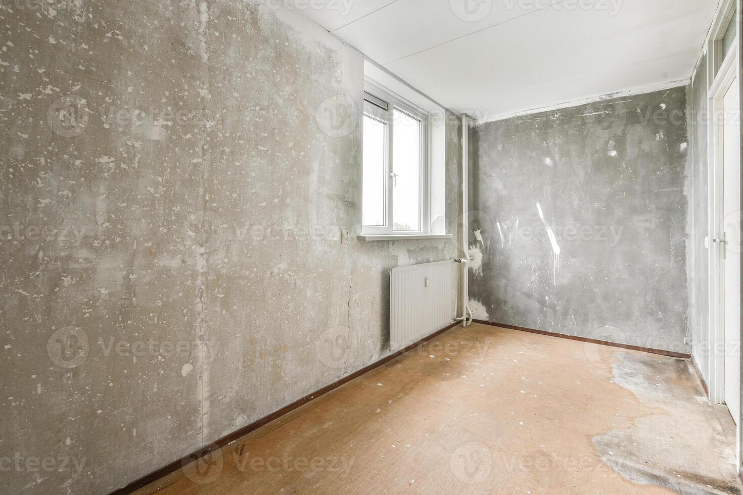 An empty room with a wall covered in cement photo