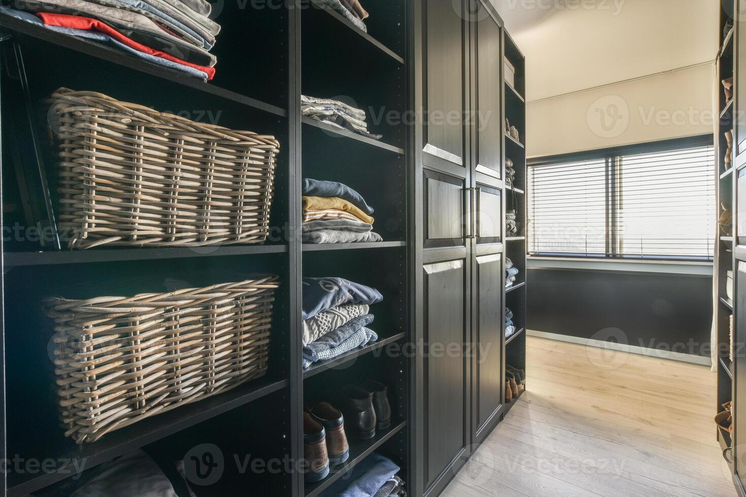 A walk in closet with black cabinets and baskets photo