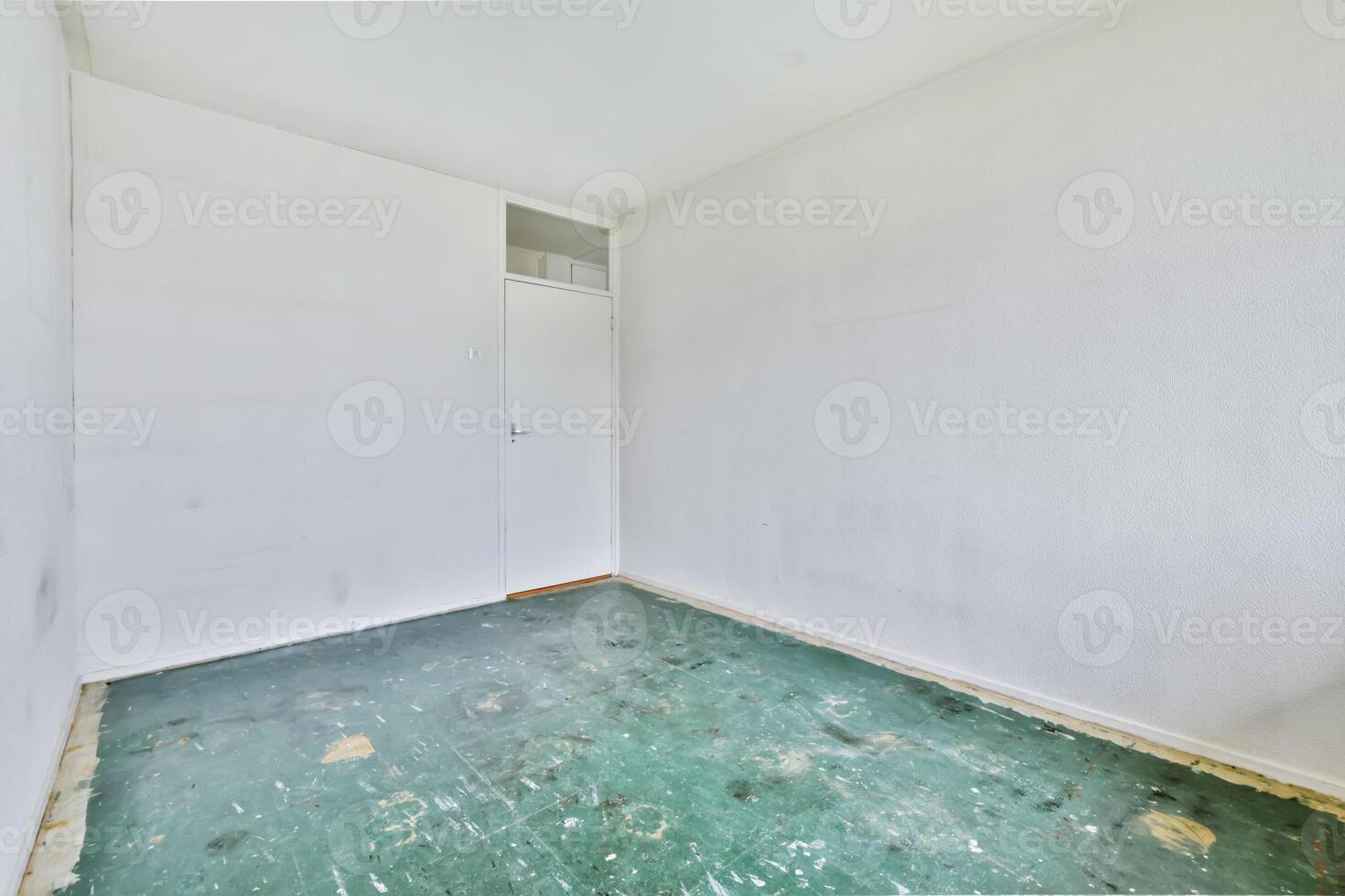 An empty room with a green floor and white walls photo