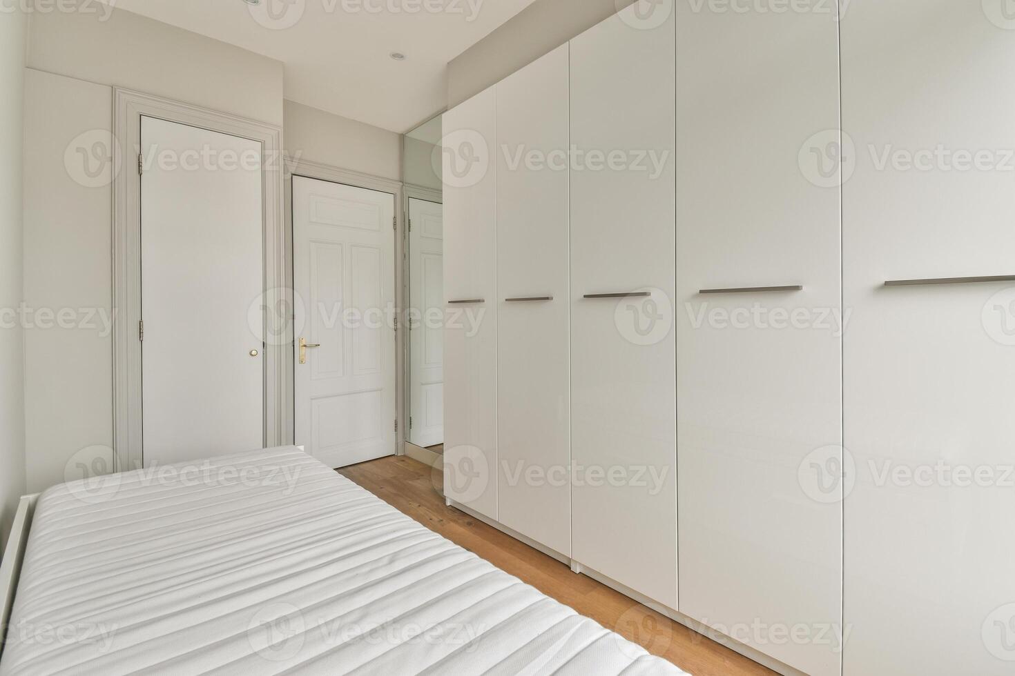 A bedroom with white cabinets and a bed photo