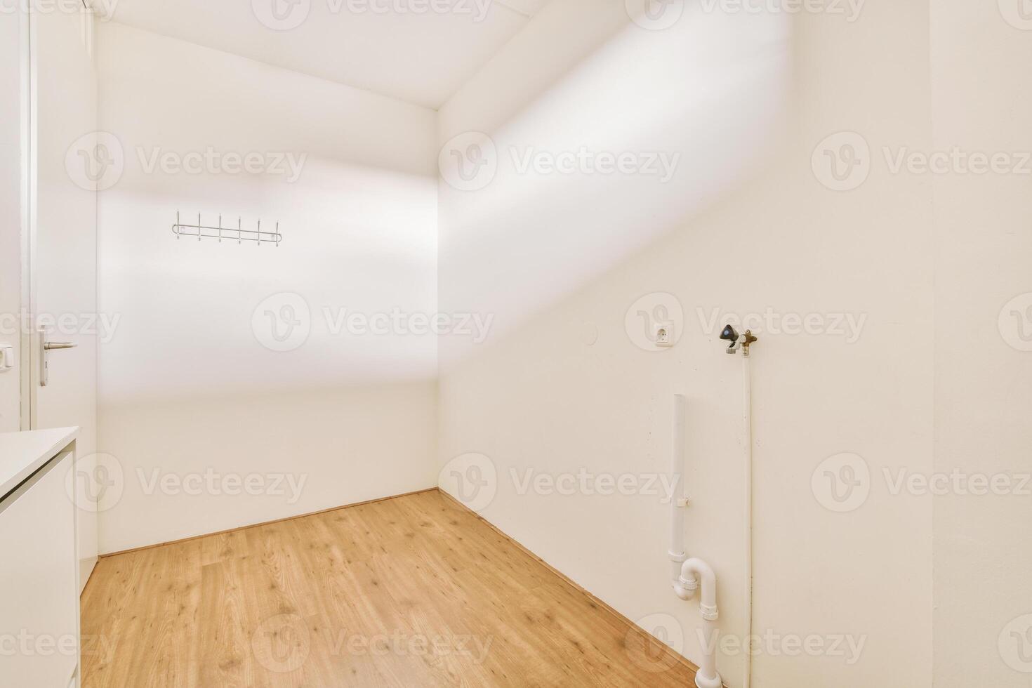 A white room with a wooden floor and a white wall photo
