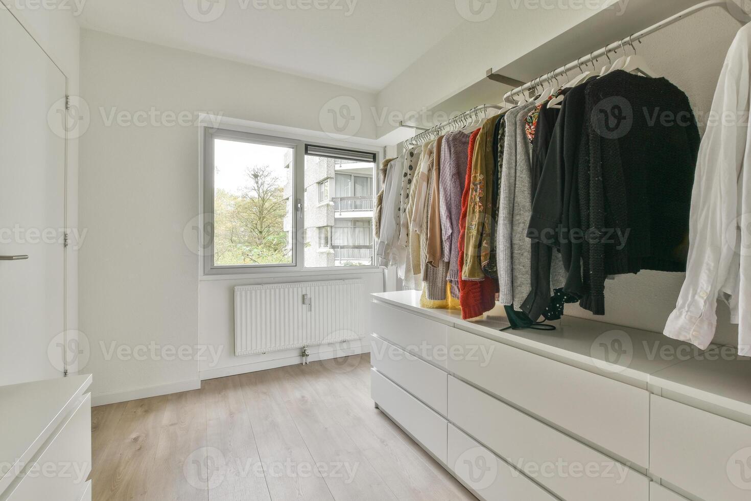 A walk in closet with white cabinets and clothes photo