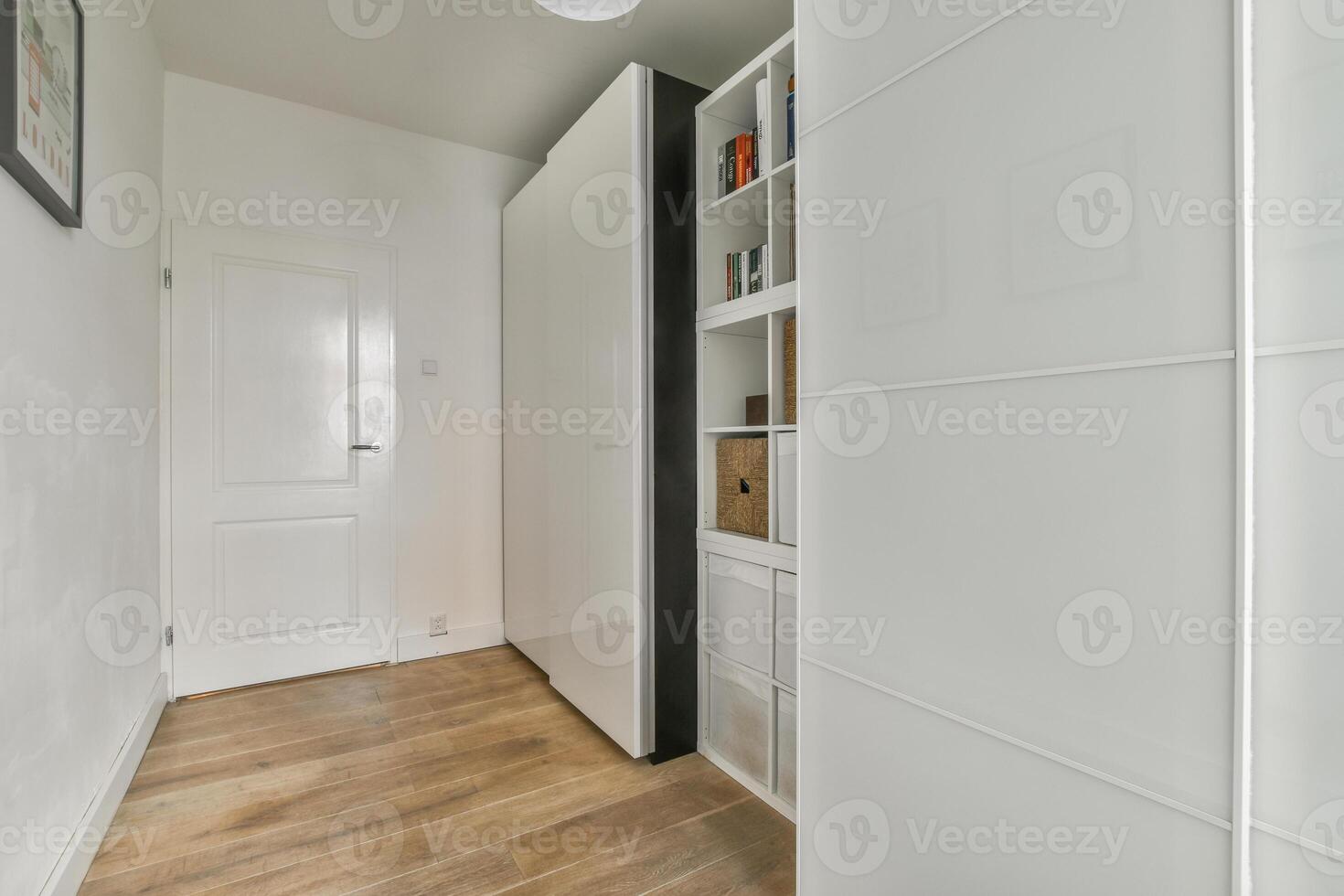 A hallway with white cabinets and a door photo
