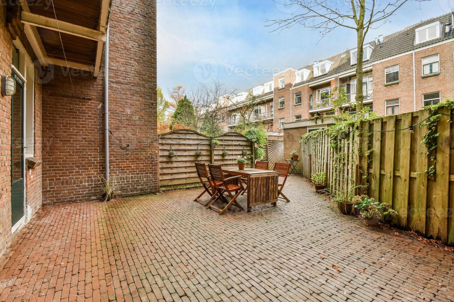 A brick patio with a table and chairs in it photo