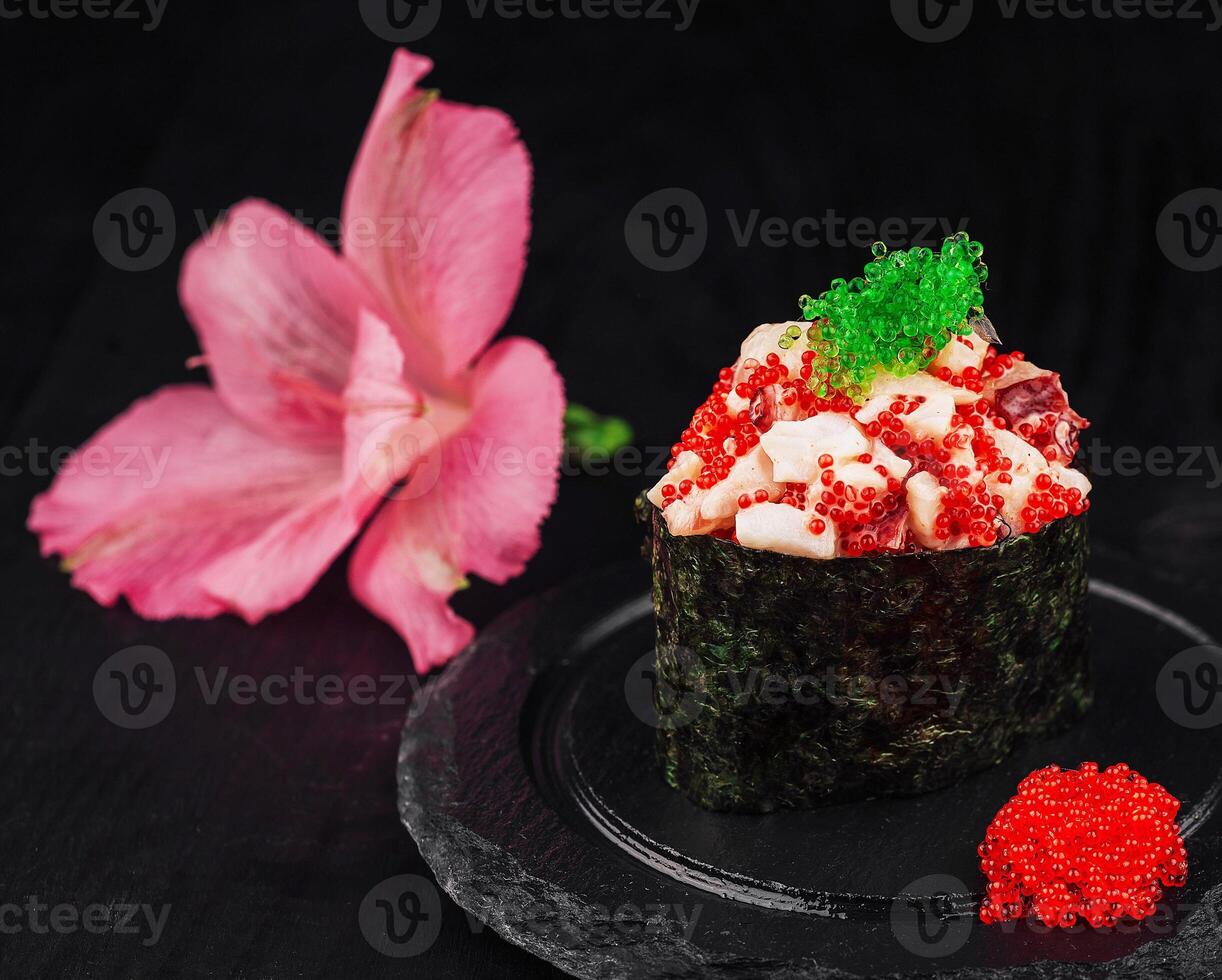 Gunkan maki sushi with tobiko and red caviar resting on a slate plate photo