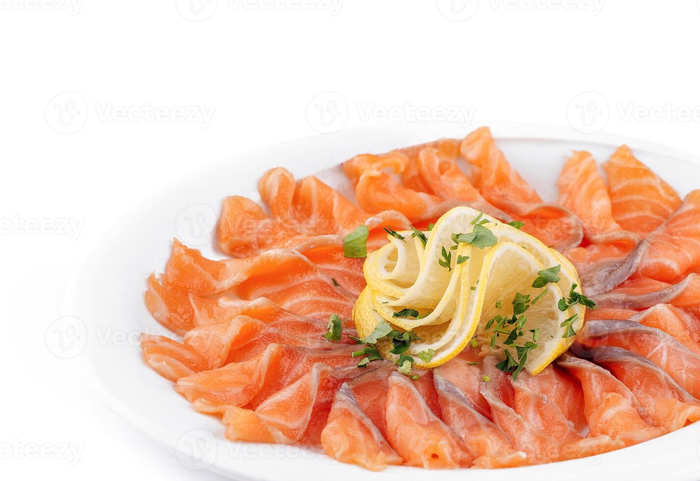 Sliced salmon fillet decorated with lemon and parsley on white plate photo