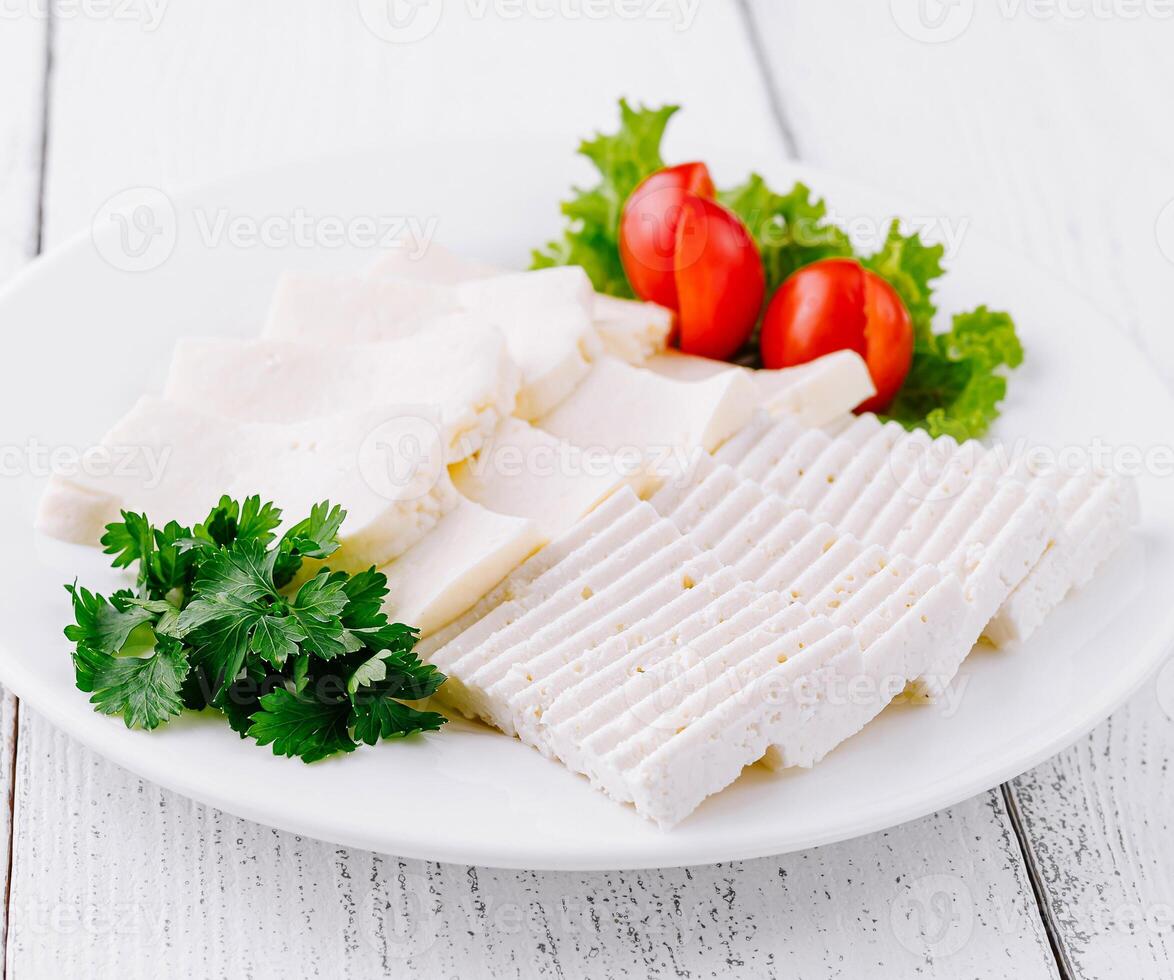 White cheese slices with cherry tomatoes and parsley on white plate photo