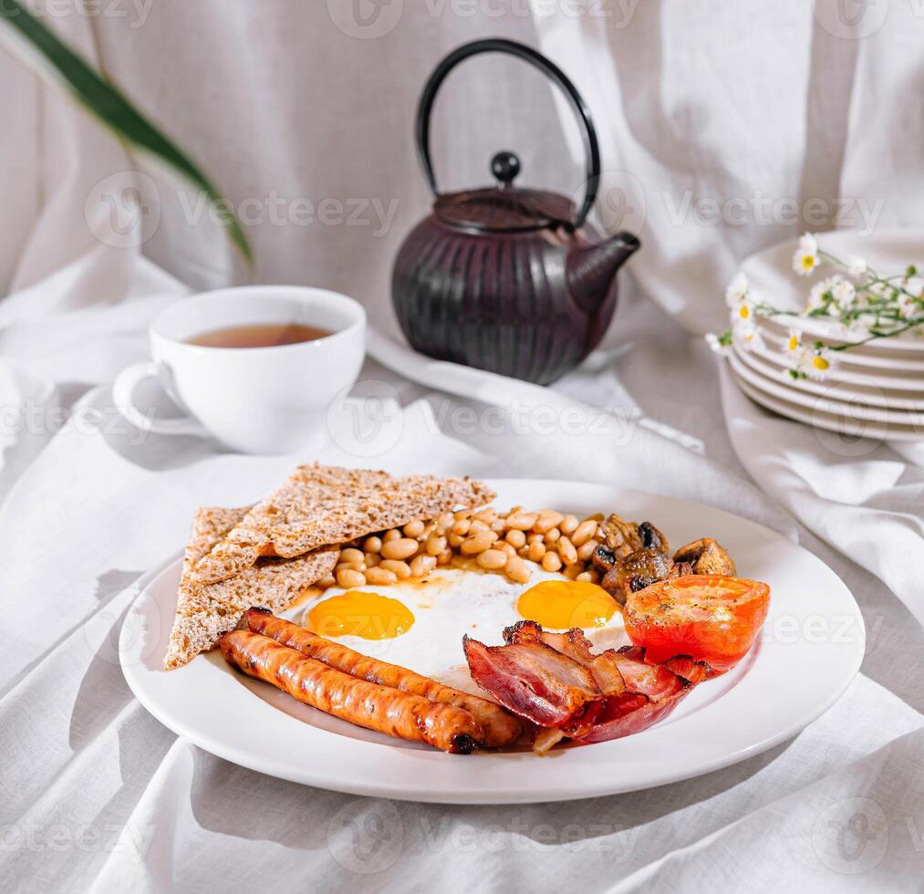 Full english breakfast with crispy bacon and sunny side up eggs being served for breakfast photo
