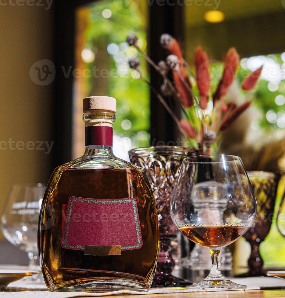 Bottle of cognac and glass are sitting on table in restaurant photo