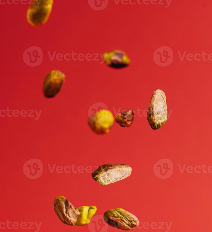 Pistachios falling down on red background photo