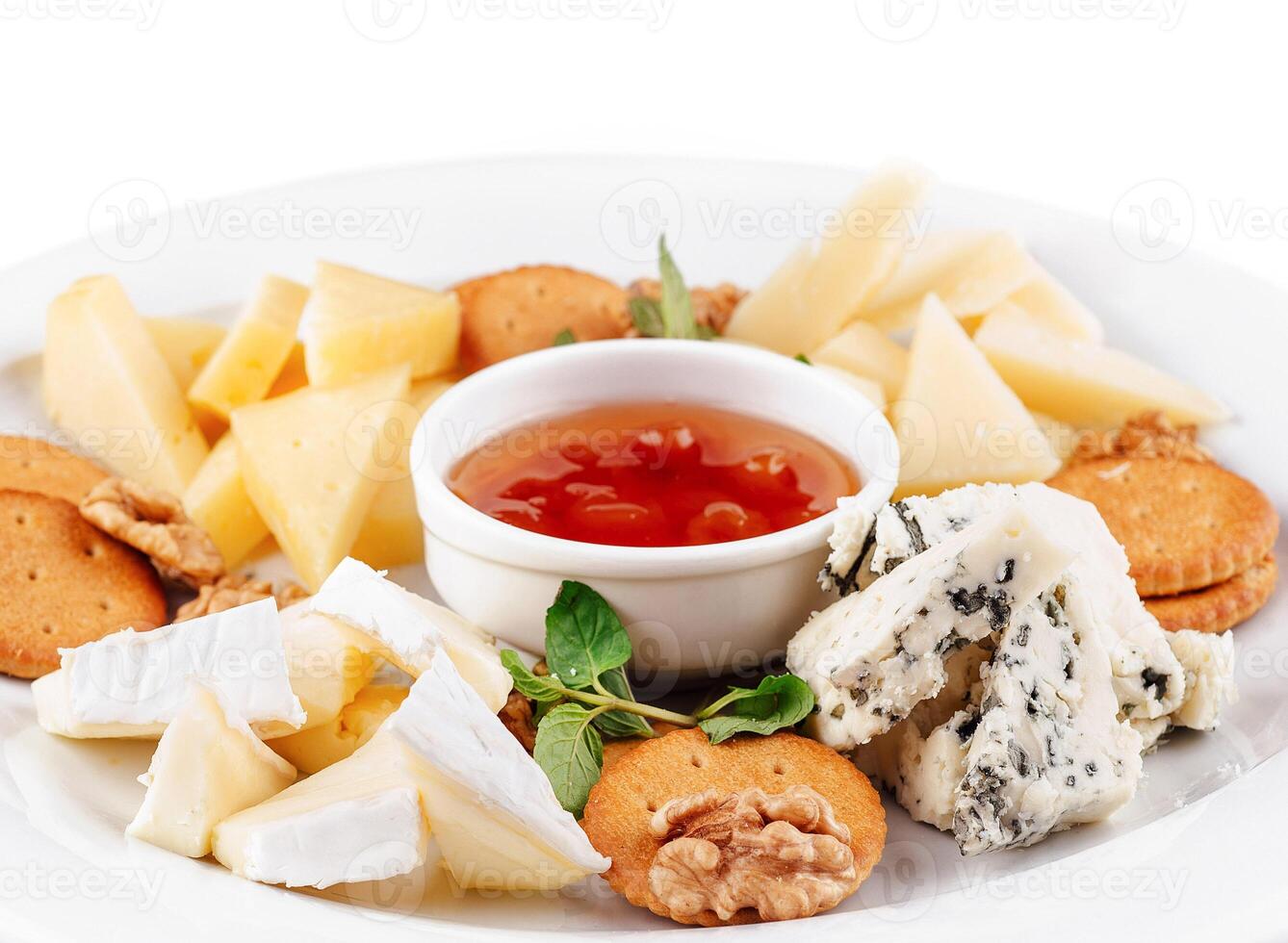 Delicious cheese plate presenting variety of cheeses, nuts, and sauce photo