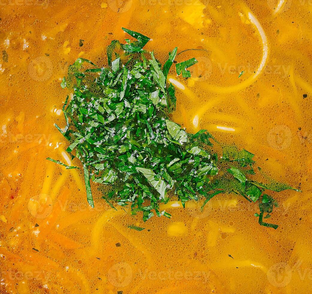 Fresh chopped parsley floating on top of chicken noodle soup photo