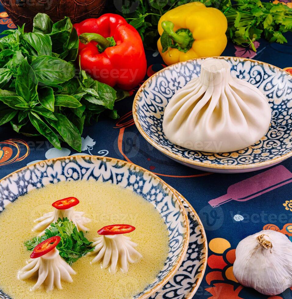 Khinkali dumplings are served on a plate with broth, herbs and spices photo