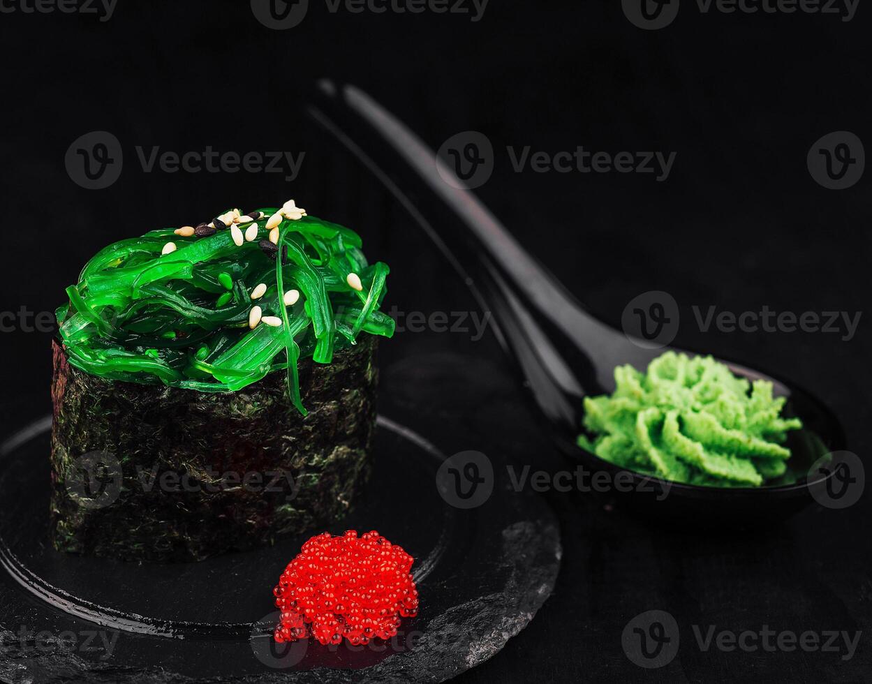 Sushi with chuka seaweed, sesame and wasabi on black background photo