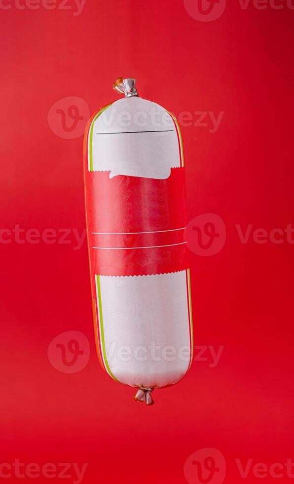 Sausage with blank label hanging on red background photo