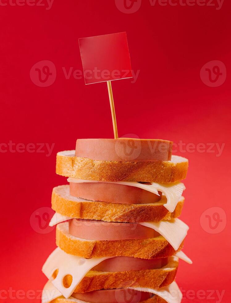 Big tower of bread and sausage with blank sign on red background photo