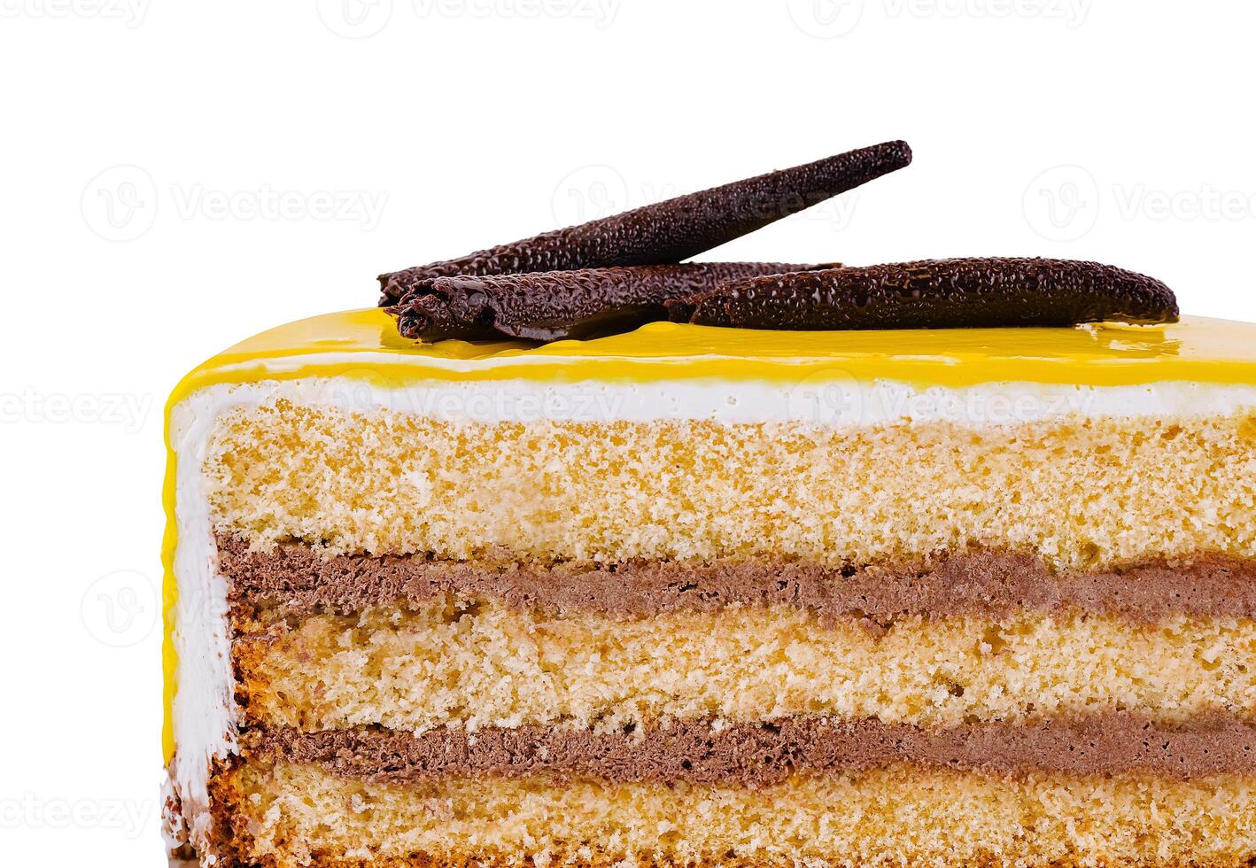 Delicious piece of cake with yellow icing and chocolate decoration isolated on white background photo