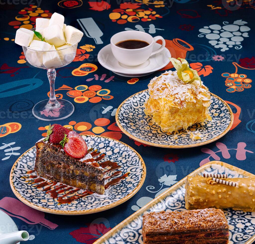 Delicious desserts and coffee on table with floral patterned tablecloth photo