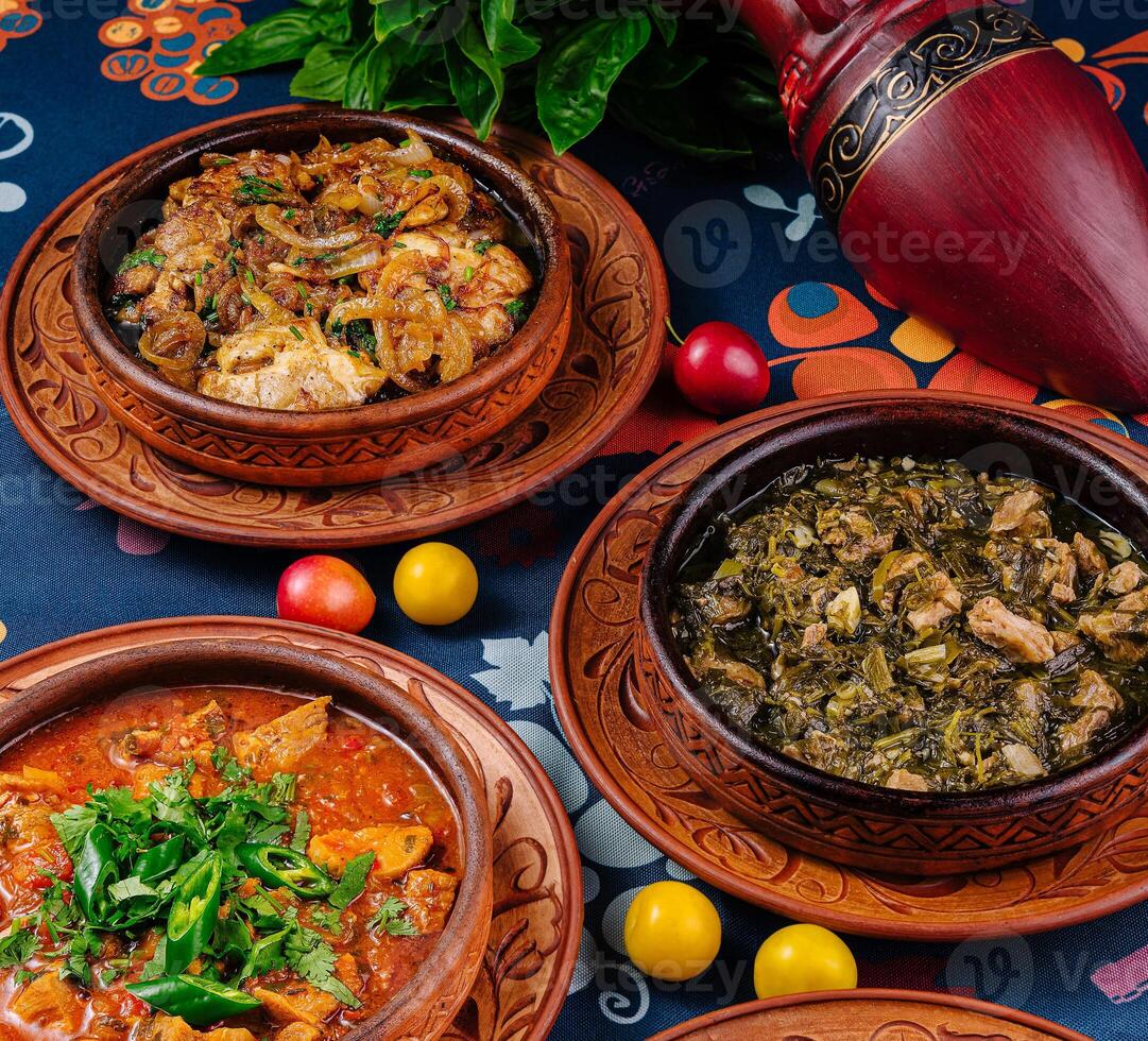 Three earthenware pots filled with delicious food from georgian cuisine standing on a table photo