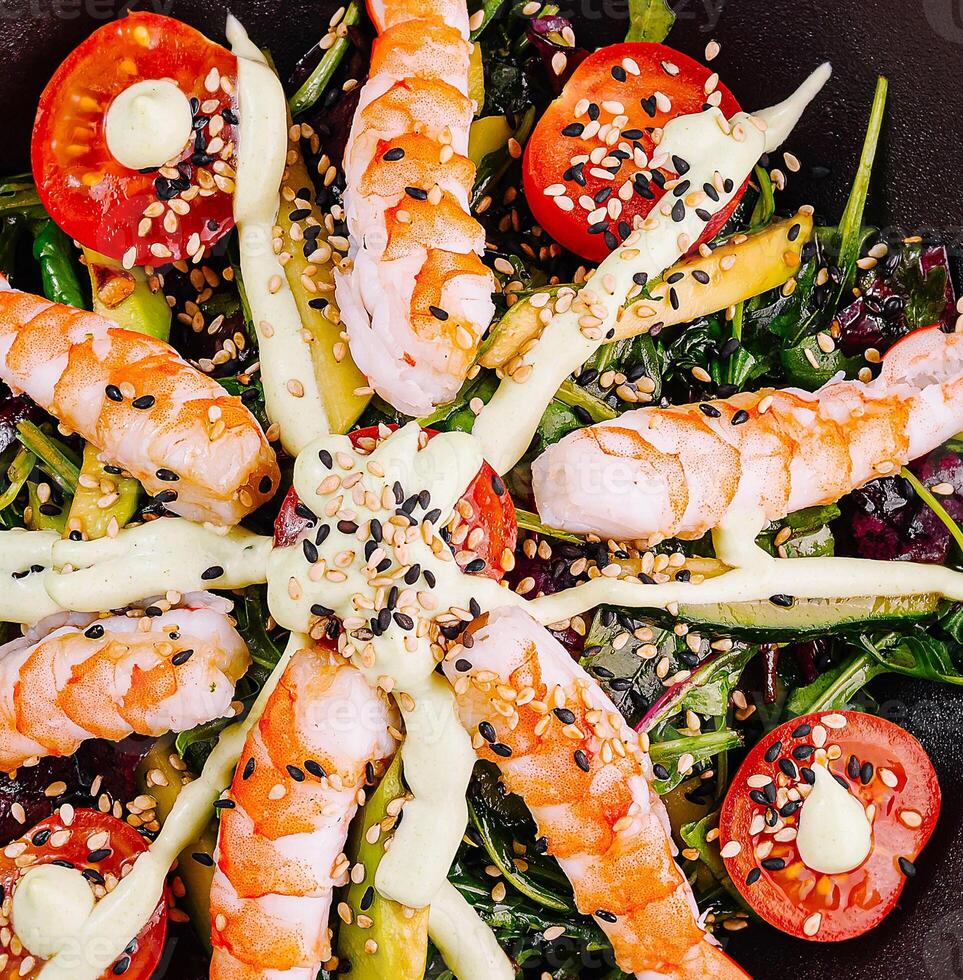 Delicious salad with shrimps, tomatoes, avocado and sauce dressing photo