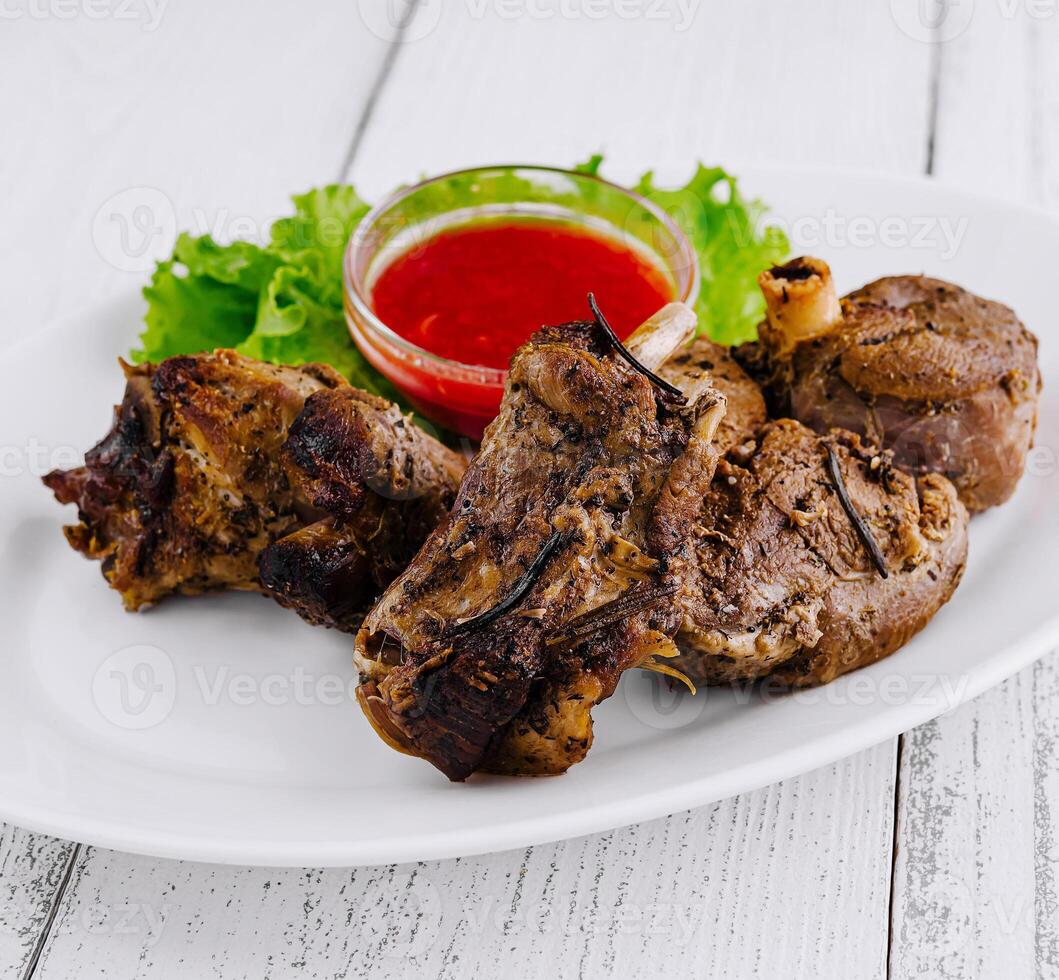 Roasted lamb shanks with rosemary and red spicy sauce on white plate photo