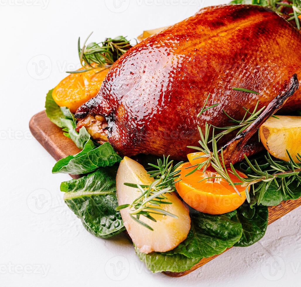 Roasted duck with oranges and herbs on wooden board photo