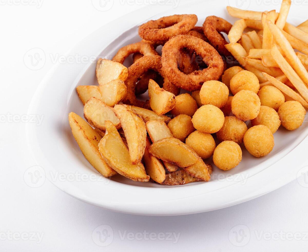 Big plate of french fries, potato wedges, onion rings and croquettes on white background photo