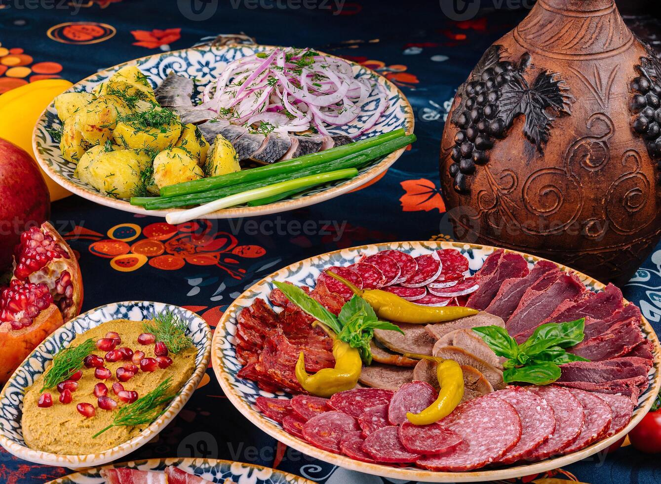 Table is set with plates of meat, fish, and sauce photo
