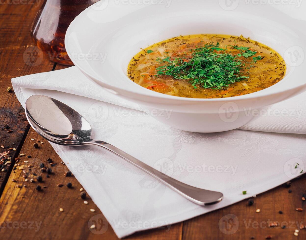 Delicious chicken soup with vegetables served on rustic wooden table photo