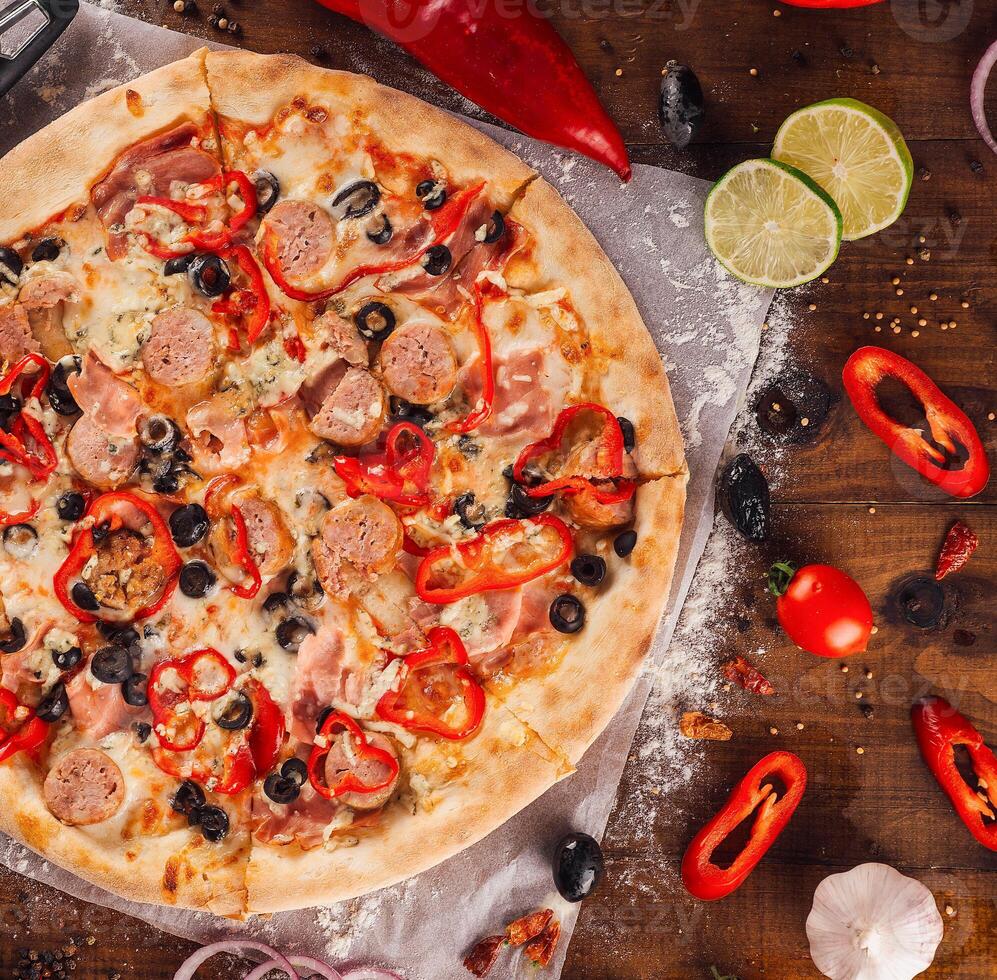 Delicious pizza with sausage and pepperoni lying on wooden table photo